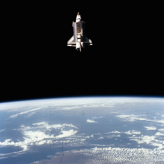 Photo of Space Shuttle Challenger in orbit above the earth